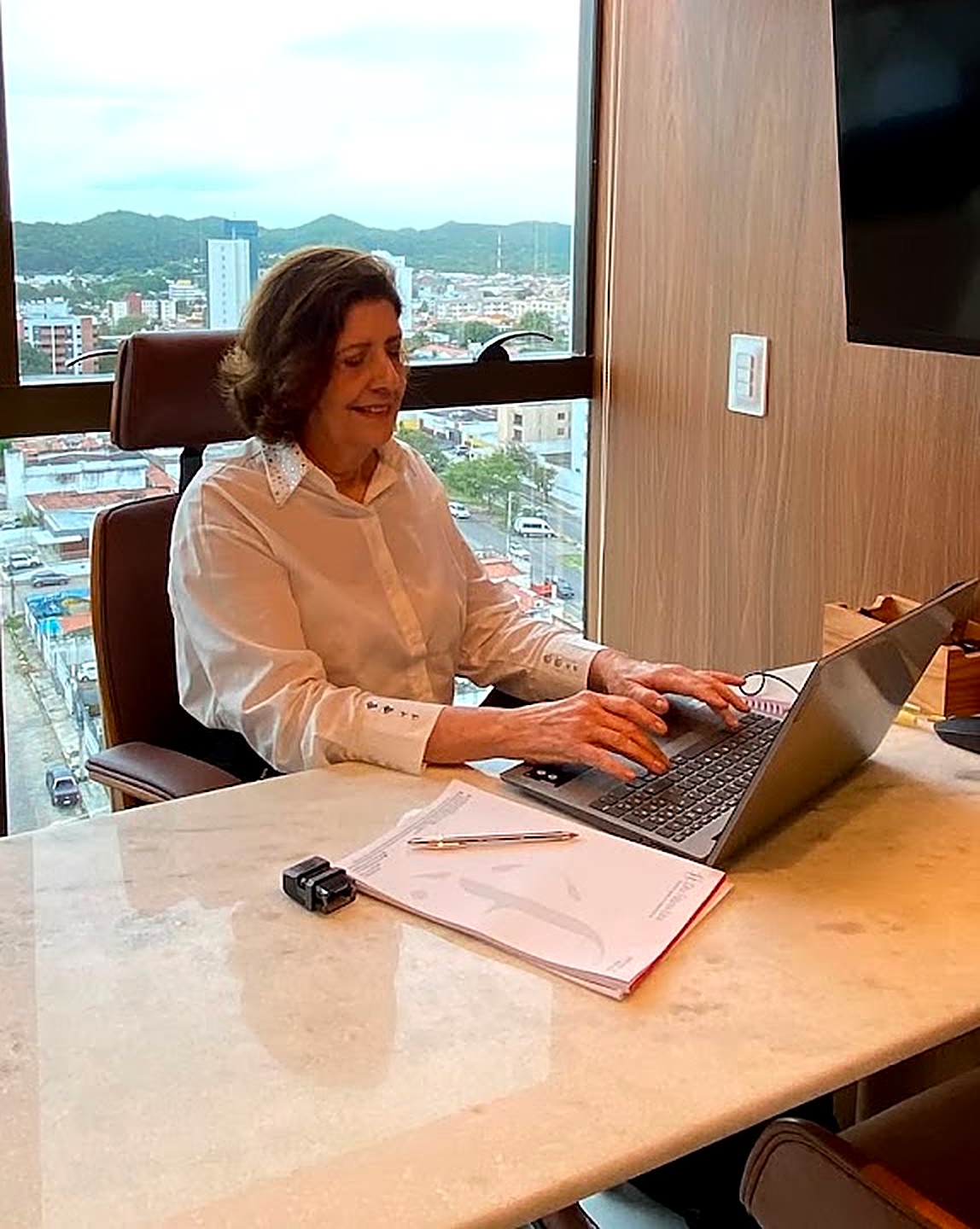 Dra. Fátima no consultório, atendendo pelo computador